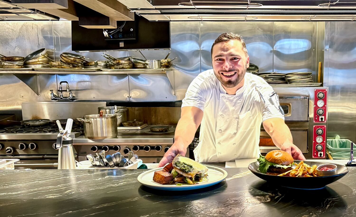Head Chef of Good Folk Victor Bonilla slides two plates of food across a table in Banff.